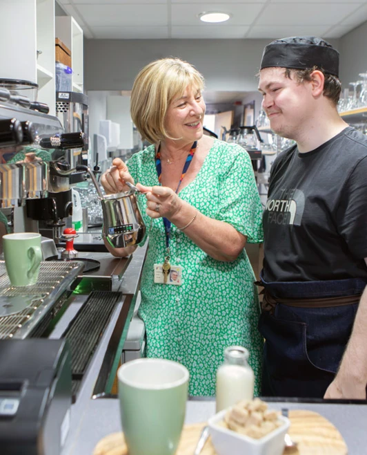 Hospitality lecturer interacting with a barista student while demonstrating a coffee-making technique at an espresso machine. Hospitality lecturer interacting with a barista student while demonstrating a coffee-making technique at an espresso machine.